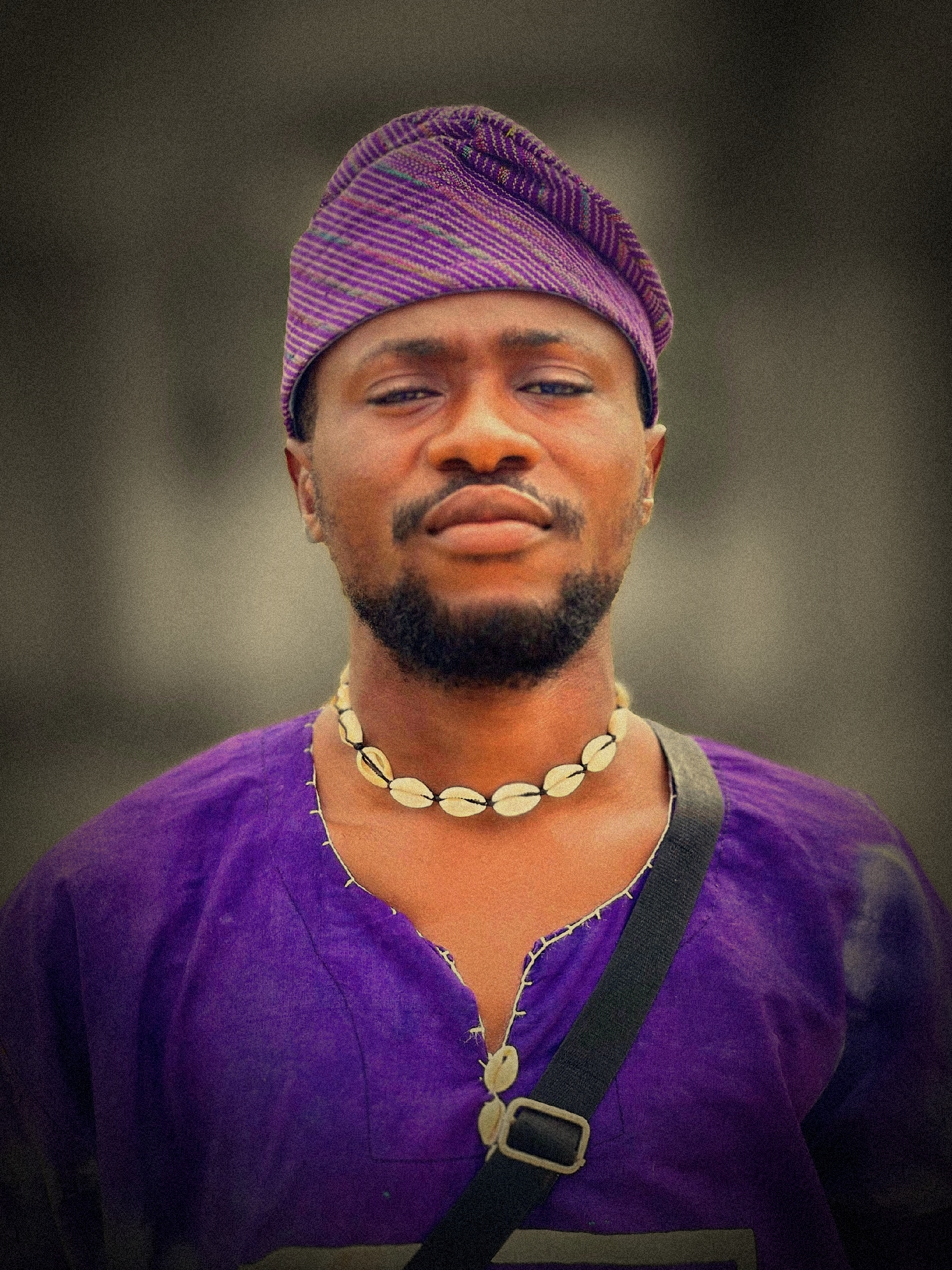 Cinematic portrait of a man in purple Yoruba attire with a cowrie necklace