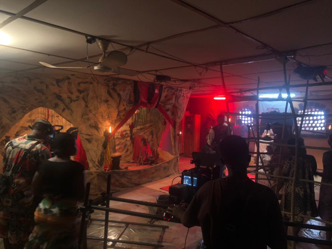 Night film set lit in deep red with a shrine scene and camera operator silhouette